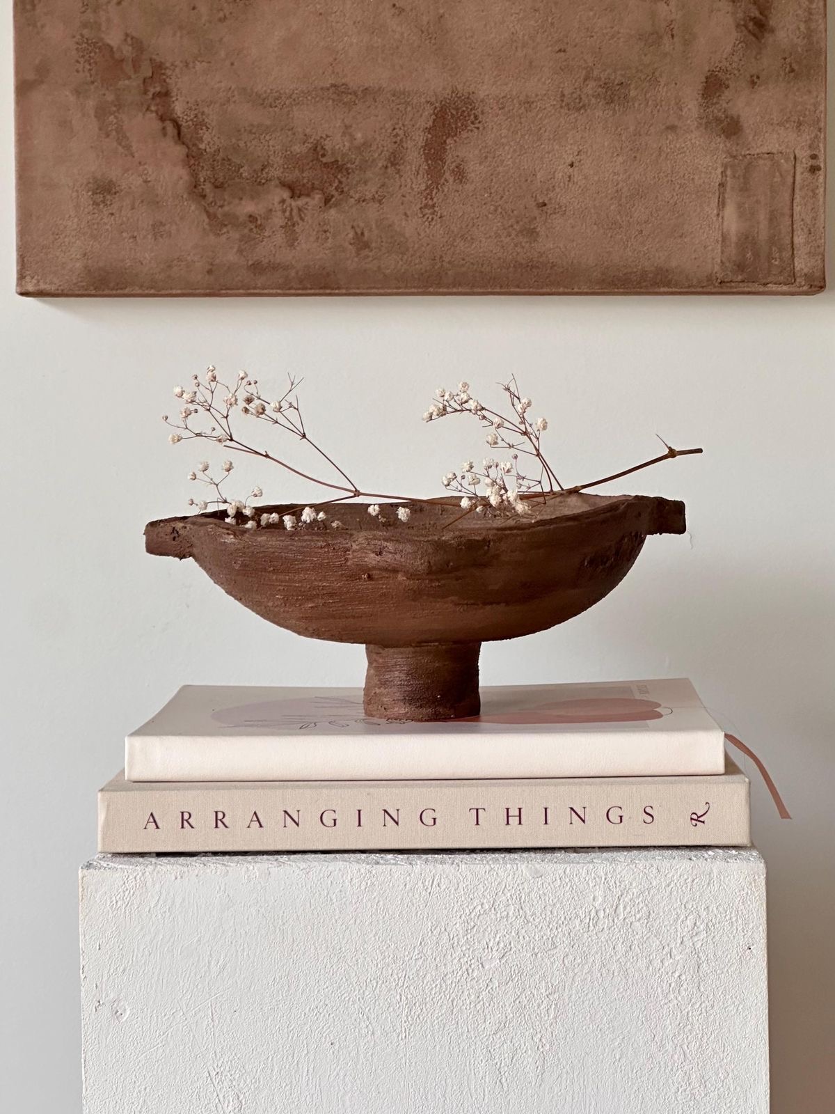Detalle de un rincón de casa con libros, cerámica y flores